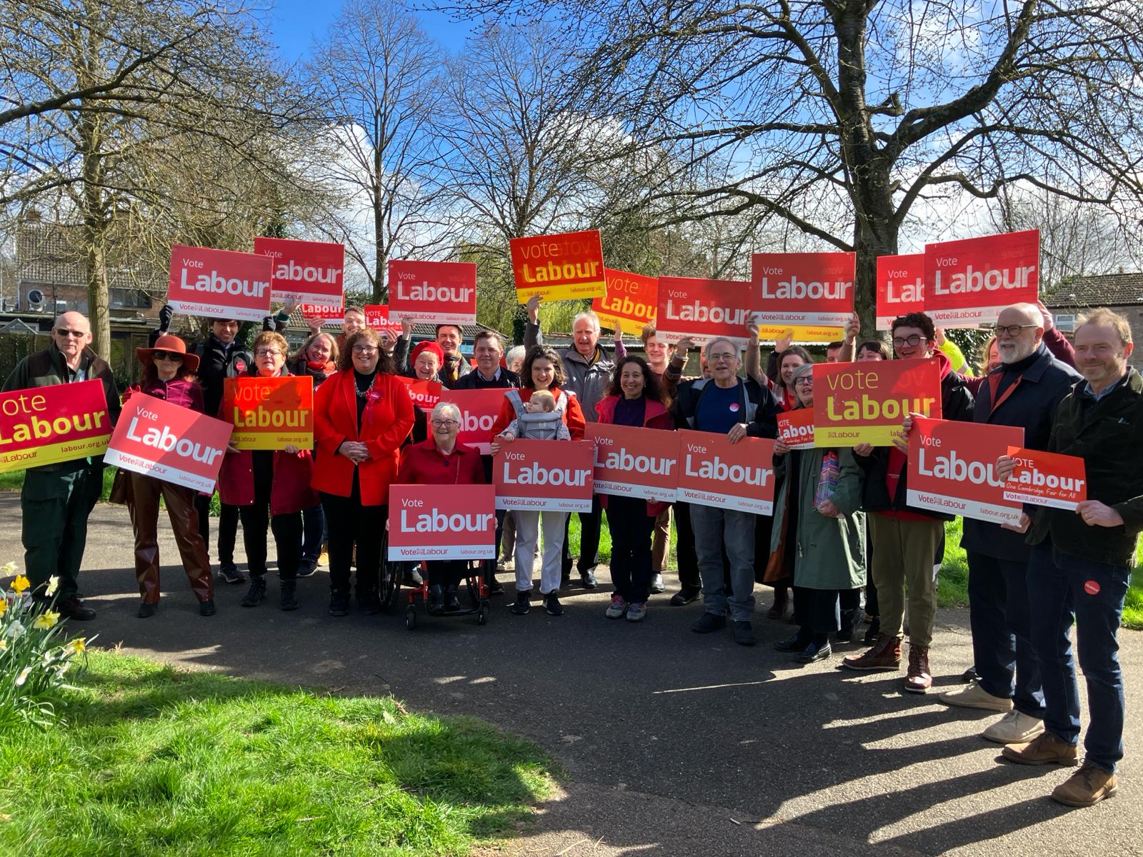Councillors and Labour members holding Labour banners in a local park